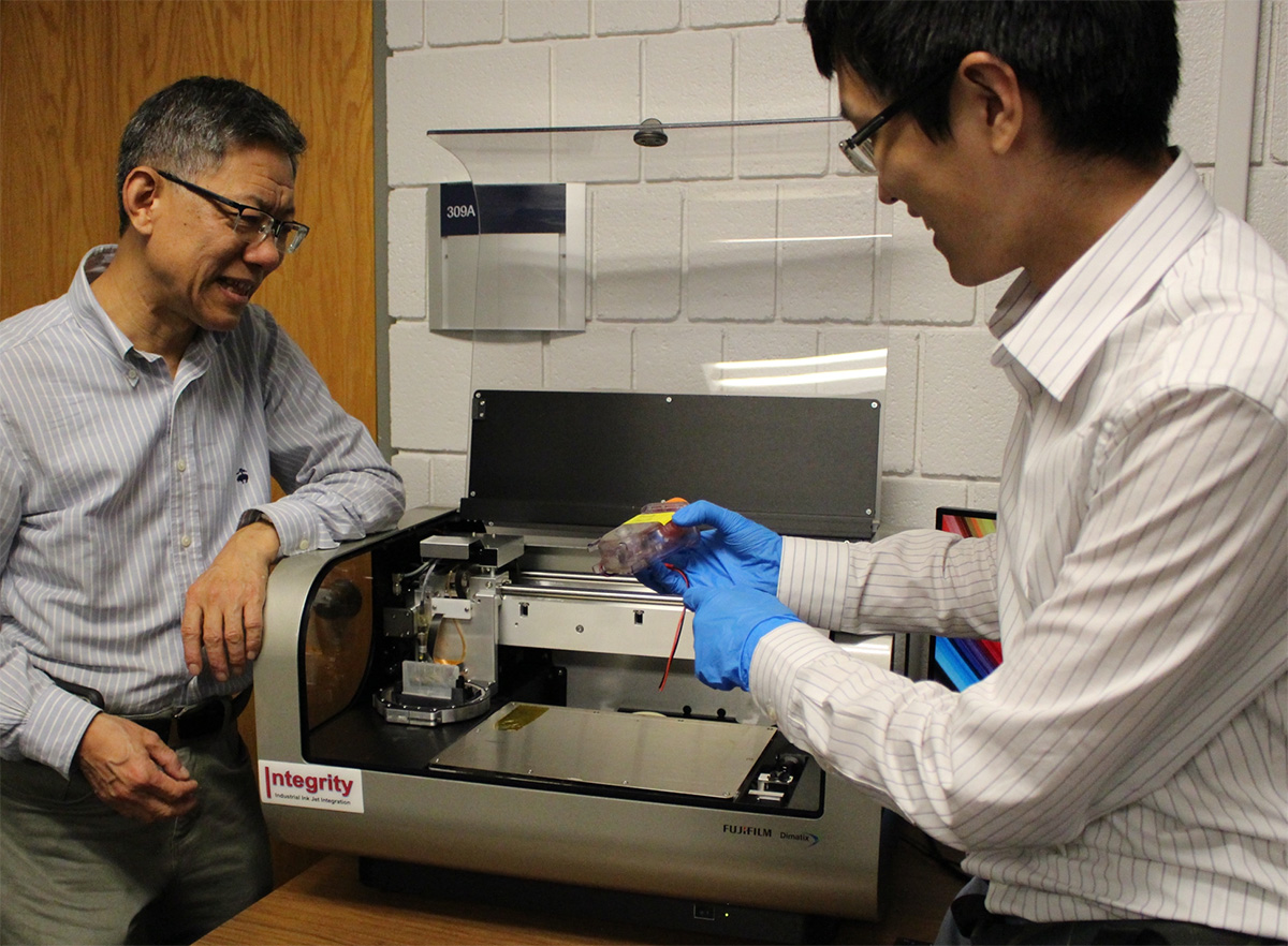 Chuck Zhang (left) and Zhaonan Liu examine a flexible biosensor