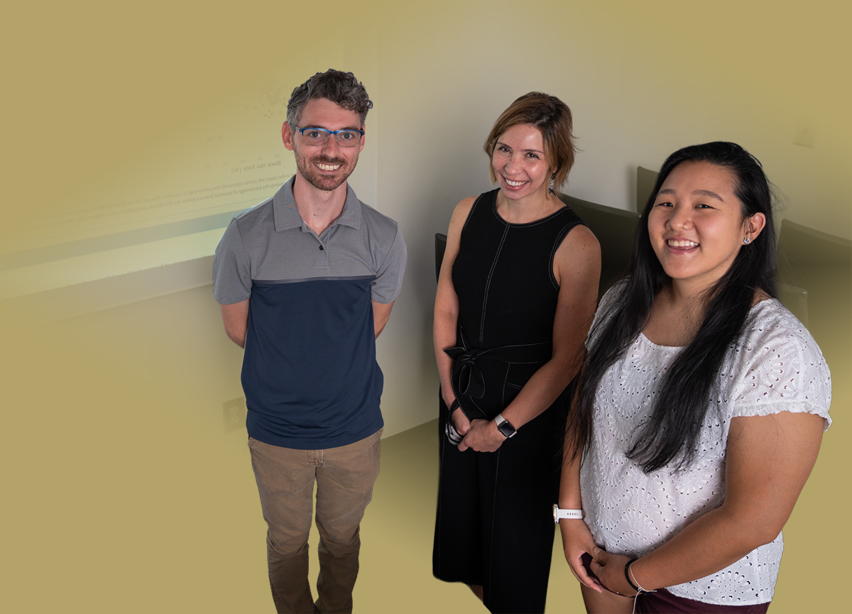 Dima standing with 2 students in a classrom