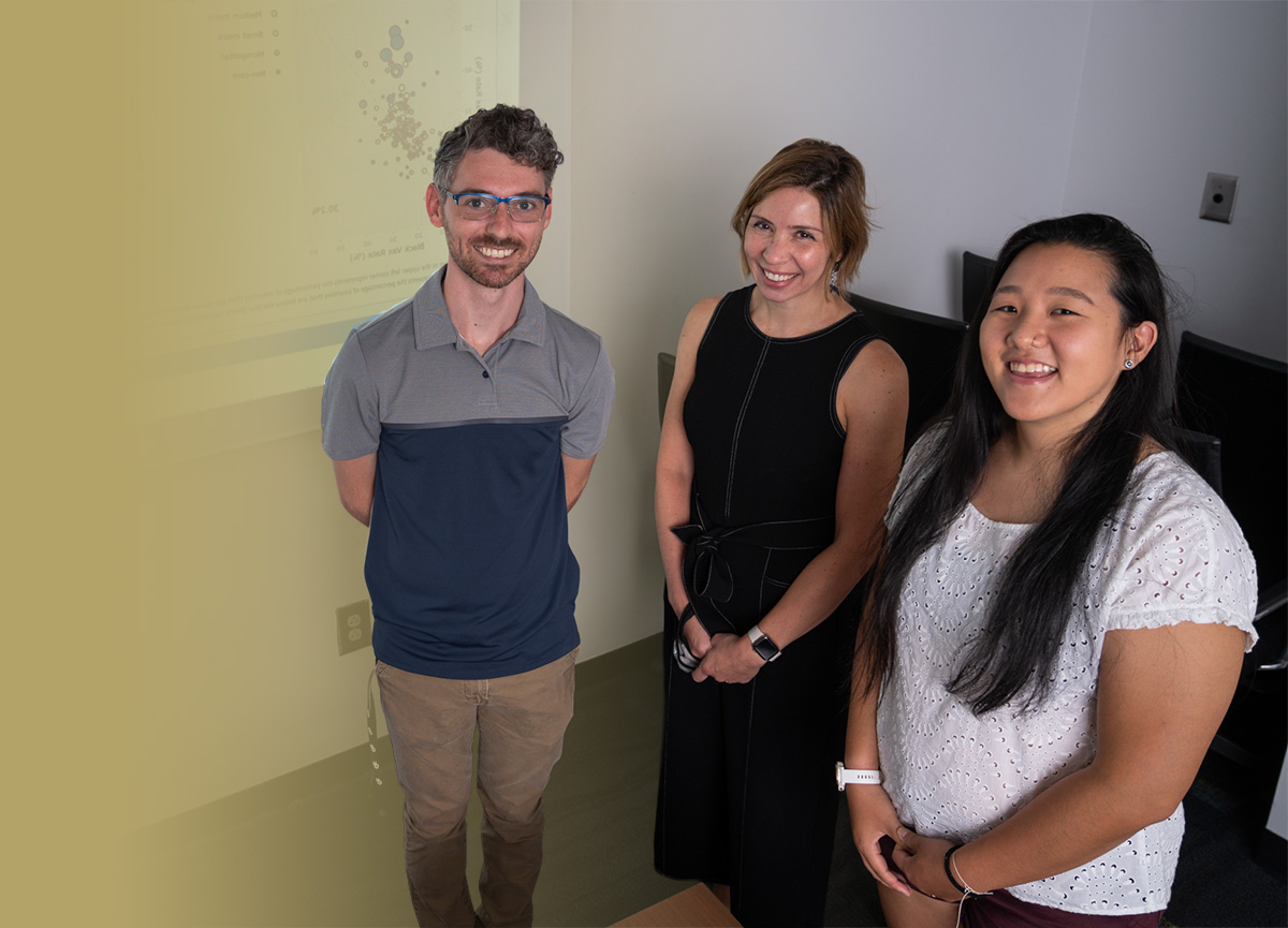 Dima standing with 2 students in a classroom